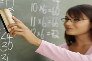 Teacher cleaning chalkboard with duster